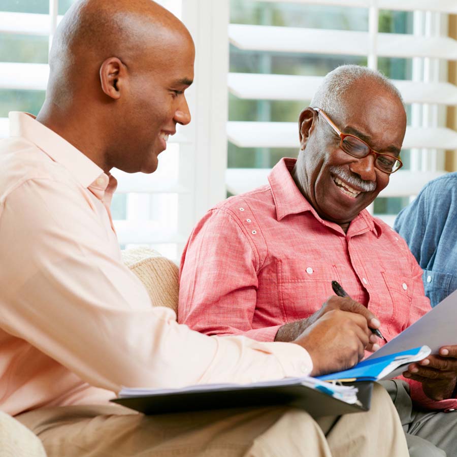 elderly man signing paperwork with a younger guy